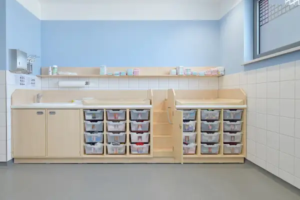 Praktische Elternecke Kita gestalten: Wickeltische, Waschbecken und viele durchsichtige Schubladen für Windeln und Kleidung.